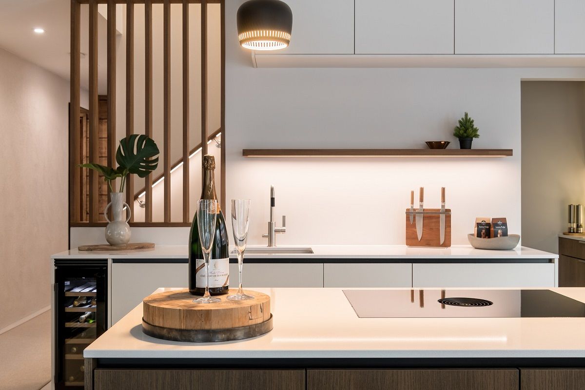 In una cucina open space, la striscia LED sotto il ripiano aperto illumina il piano di lavoro